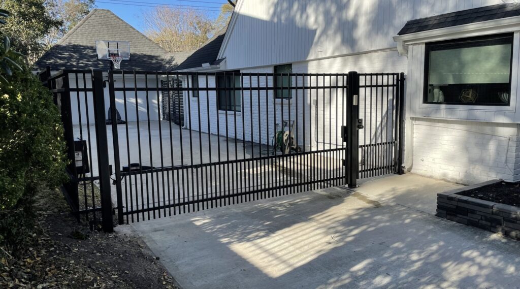 Electric iron driveway gate beside a modern stucco home