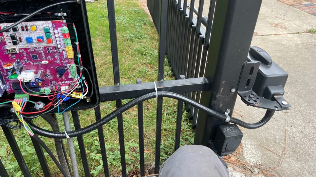 Gate operator control box opened during service, showing internal wiring and circuit board