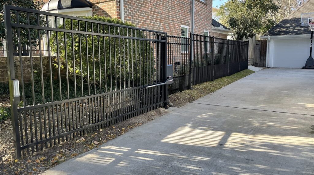 Iron driveway gate and matching fence at a two-story brick home