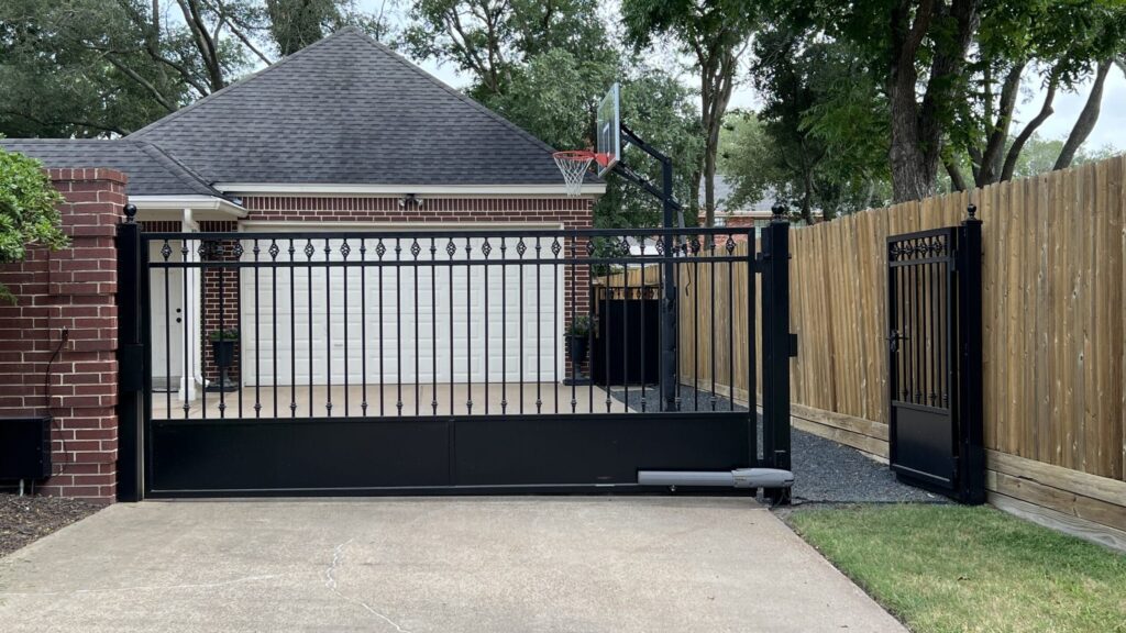 Black iron driveway gate and matching pedestrian gate automated with a Viking operator