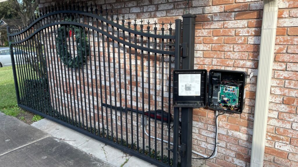 Iron slide gate along a brick wall with the operator control board opened for service