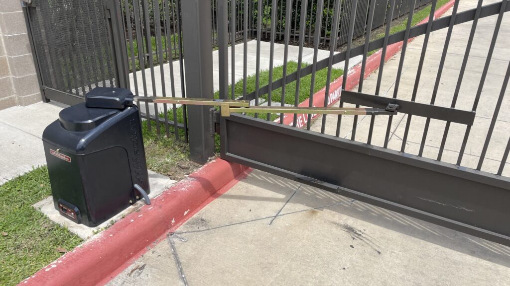 LiftMaster CSW24 slide gate operator installed at a commercial driveway with a painted curb