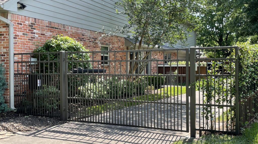 Bronze iron picket driveway gate and matching fence at a brick ranch home in Pasadena, TX