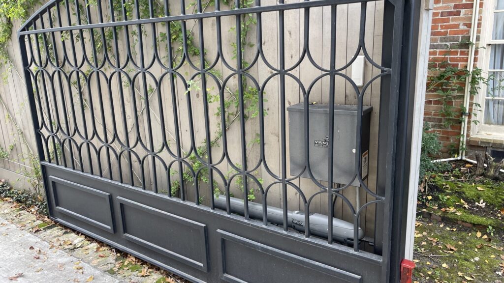 Ornamental iron swing driveway gate with scrollwork panels
