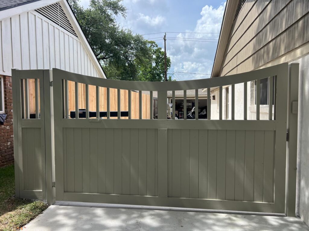 Sage green wood driveway gate with arched slat top and matching pedestrian gate