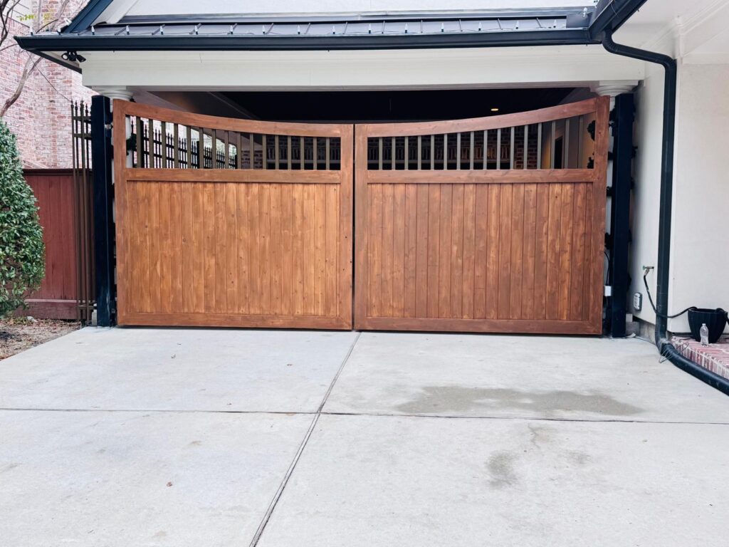 Stained wood double gate with arched spindle top set in a black steel frame