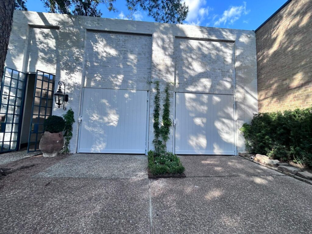 White carriage-style swing doors on a whitewashed brick courtyard wall